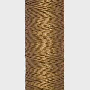 Puede incluir: Una bobina de hilo Gütermann de color marrón cálido. El hilo está enrollado firmemente alrededor de un núcleo cilíndrico. La bobina tiene una parte superior e inferior verdes con el nombre de la marca y la longitud del hilo impresos. El hilo mide 30 metros.