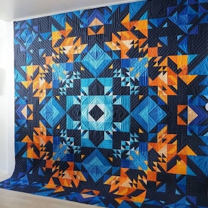May include: A large quilt with a geometric pattern in shades of blue, orange, and black. The quilt is made up of many different shapes and sizes, creating a complex and intricate design.