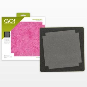 May include: A fabric cutting die set with a black base and gray cutting surface. The packaging features the "GO!" logo and a pink patterned fabric sample. The die cuts 8-inch squares.