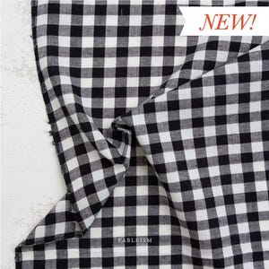 May include: Black and white gingham fabric with a classic checkered pattern. The fabric is folded, showing texture and depth. The word "NEW!" is displayed in a red banner. The brand name "FABLEISM" is visible.