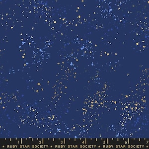 Op de afbeelding: Een donkerblauwe stof met een verspreid patroon van kleine goud- en lichtblauwe verfspatten. Aan de onderkant is een zwart meetlint zichtbaar met markeringen van 1 tot 7 inch en de tekst RUBY STAR SOCIETY.