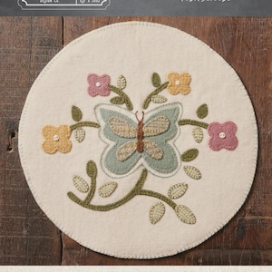 May include: A round, off-white mat with a butterfly and floral design. The butterfly is light blue and tan, surrounded by pink and yellow flowers and green stems. The mat is 10.5 inches in diameter. The text "FLOWERS & BUTTERFLY MAT" is at the bottom.