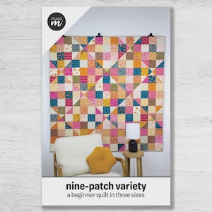 May include: A colorful nine-patch quilt with a variety of fabrics in pink, orange, teal, and yellow. The quilt is displayed on a wall. The image also shows a white chair, a small table, and a lamp. The text reads "nine-patch variety" and "a beginner quilt in three sizes."