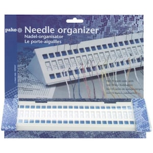 May include: A white plastic needle organizer with the text "Needle organizer" and "pako" on the packaging. The organizer has a keyboard-like design with multiple holes for holding needles and threads. Includes 10 blank code cards.