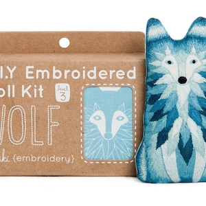 May include: A DIY embroidered doll kit with a blue and white wolf design. The kit includes a brown cardboard box with the text "D.I.Y Embroidered Doll Kit WOLF" and a level 3 difficulty rating. The finished doll is a blue and white embroidered wolf.