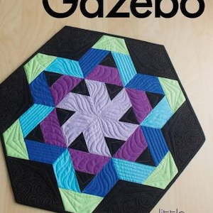 May include: A hexagonal quilt with a geometric design in shades of blue, purple, green, and black. The quilt is quilted with a swirling pattern and has a black border with a decorative swirl design. The quilt is titled "Gazebo" and is made by Little Jaybird Quilts.