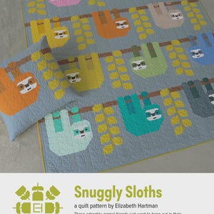 May include: A light blue quilt and pillow set featuring colorful sloth designs hanging from branches. The sloths are in various colors, including pink, orange, and green. The quilt has a repeating pattern of sloths and branches. The text "Snuggly Sloths" is visible.