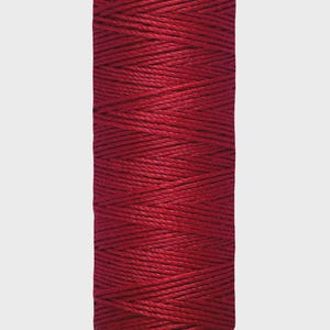 May include: A spool of Gütermann red thread. The spool is cylindrical, with a green base and top. The thread is a deep, rich red color, and the label reads "30 m - 33 yds/vgs".