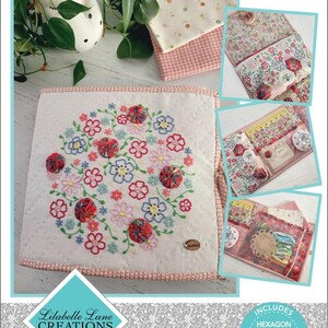 May include: A white project folder with floral embroidery and the text "Take Me There." The folder features a circular floral design with red, pink, and blue flowers. Includes hexagon template, EPP papers, and yoyo template.
