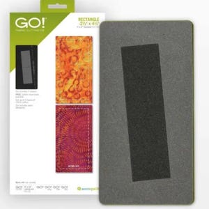 Könnte beinhalten: Eine graue Stoffschneideschablone mit einem schwarzen rechteckigen Ausschnitt, neben einer Verpackung mit Stoffrechtecken in orangefarbenen und lila Mustern. Auf der Verpackung steht "GO! Fabric Cutting Die" und "RECTANGLE -6.35cm x 11.43cm"