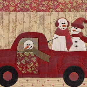 Puede incluir: Un cami&oacute;n de juguete rojo con tres mu&ntilde;ecos de nieve. El mu&ntilde;eco de nieve en el asiento del conductor lleva una bufanda verde. Los dos mu&ntilde;ecos de nieve en la parte de atr&aacute;s llevan bufandas rojas. El cami&oacute;n est&aacute; sobre un fondo estampado.