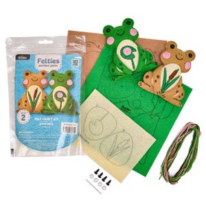 Puede incluir: Un kit de manualidades de fieltro para hacer amigos del estanque, con diseños de ranas y juncos. El kit contiene fieltro verde, marrón y beige, hilo, patrones y pequeños cierres negros. El embalaje muestra dos diseños de ranas de fieltro terminados.