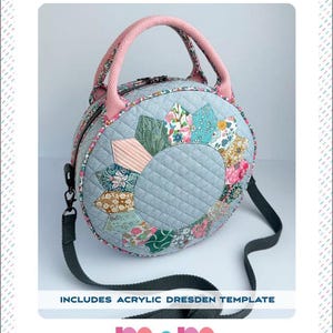 Puede incluir: Bolso redondo acolchado con diseño floral y asa rosa. El bolso tiene una correa para el hombro desmontable. El texto "CARRY ROUND" y "CIRCLE CROSS BODY OR HAND HELD BAG" es visible. Incluye una plantilla Dresden acrílica.
