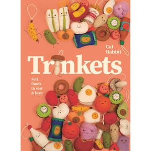Może przedstawiać: Kolekcja filcowych zawieszek spożywczych, w tym banan, jajko, awokado i pomidor, na koralowym tle. Słowo "Trinkets" wyświetlane jest dużymi białymi literami, z tekstem "Felt foods to sew & love" poniżej.