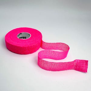 May include: A roll of bright pink athletic tape with a mesh-like texture. The tape is partially unrolled, revealing a length of the same pink material. The tape is on a white background.