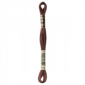 May include: A spool of DMC embroidery floss in color 779, a deep reddish-brown shade. The floss is wound around a white card with the DMC logo and the color number printed on it.