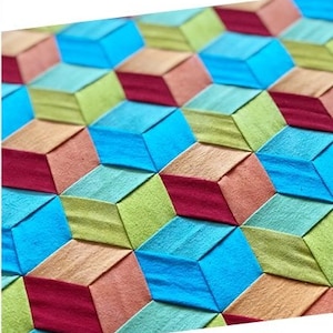 May include: A fabric weaving pattern called "Tumbling Trifecta" by Wefty. The pattern features a repeating design of colorful cubes in shades of blue, green, red, and orange.
