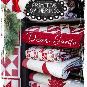 Puede incluir: Una pila de tela acolchada roja y blanca con las palabras "Querido Santa" bordadas en la pieza superior. La tela está en un estante con un letrero que dice "Primitive Gatherings" encima.