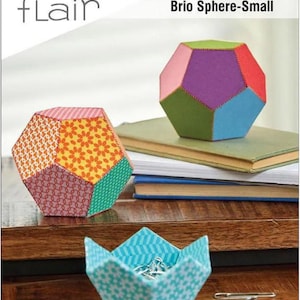 Puede incluir: Un kit de patchwork de papel para crear una esfera o un cuenco facetado de 9,5 cm. El kit incluye plantillas e instrucciones para crear dos proyectos. La imagen muestra una esfera y un cuenco coloridos hechos con el kit.
