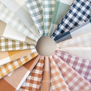 May include: A collection of 12 different gingham fabric swatches in various colors, including green, blue, yellow, orange, pink, and white. The swatches are arranged in a circle, with the edges of each swatch overlapping.