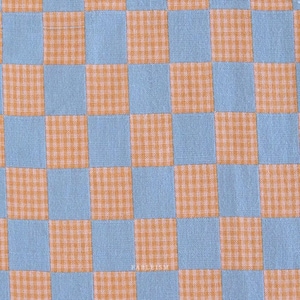 May include: Close-up of a fabric with a checkered pattern. The design features alternating squares of light blue and orange gingham. The fabric has a textured appearance, suggesting it may be cotton or a similar material. The overall aesthetic is reminiscent of a picnic blanket.