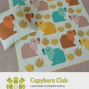 May include: A quilt and pillow set featuring a repeating pattern of colorful capybara figures. The capybaras are in shades of orange, yellow, pink, and teal, set against a light green background. The text "Capybara Club" is visible.