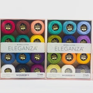 Puede incluir: Cuatro cajas de hilo de bordar colorido, cada una con 12 madejas. Las cajas están etiquetadas como "ELEGANZA" y "WONDERFUL". Los colores del hilo incluyen rosa, naranja, amarillo, verde, azul, morado, blanco y marrón.