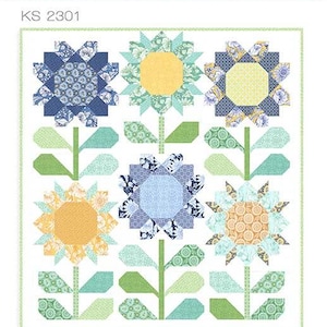 May include: A quilting pattern featuring a floral design with blue, yellow and green flowers. The pattern is titled "Bloom" and has the number "KS 2301" printed on it. The pattern is by Kate Spain.