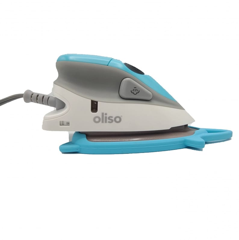 Puede incluir: Una plancha de mano peque&ntilde;a, azul y gris con una base blanca. La plancha tiene un cable y un bot&oacute;n en el lateral. La base de la plancha tiene la palabra "oliso" impresa.