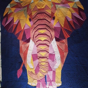 Può includere: Una trapunta colorata a patchwork che raffigura un elefante con intricati motivi geometrici in tonalità di rosa, giallo e rosso. L'elefante è in piedi su uno sfondo blu scuro.