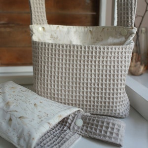 May include: Two beige waffle-weave fabric storage baskets with white floral print lining. The larger basket has two handles and the smaller basket has one handle.