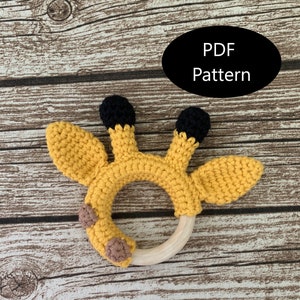 May include: A crocheted giraffe rattle with a wooden ring. The giraffe is yellow with black spots and brown ears. The rattle is a great toy for babies.