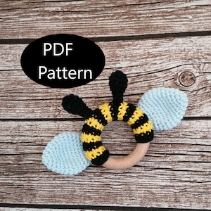 May include: Crochet bee rattle toy with black and yellow stripes, blue wings, and a wooden ring. PDF Pattern included.
