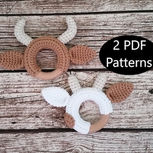 May include: Two crocheted cow rattle toys with wooden rings. The toys are brown and white and have a 3D effect. The text "2 PDF Patterns" is on a black oval in the background.