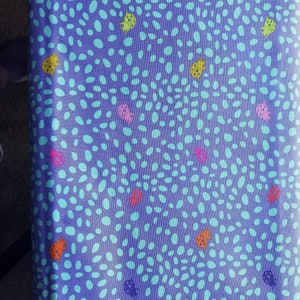 May include: Purple fabric with a repeating pattern of light blue ovals and colorful ladybugs.
