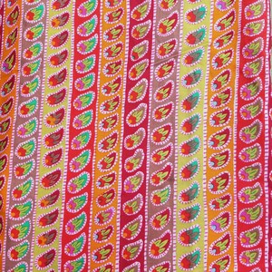 May include: A colorful fabric with a repeating pattern of teardrop shapes in shades of red, orange, yellow, green, and pink. The teardrop shapes are outlined in white and have small flower-like designs inside.