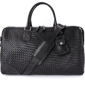 May include: A black leather woven duffel bag with a top handle and an adjustable shoulder strap. The bag has a small zippered pocket on the front.
