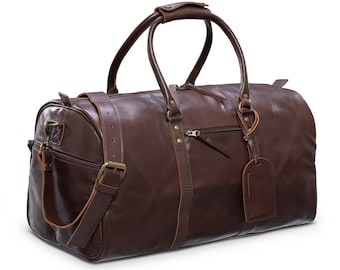 Puede incluir: Una bolsa de viaje de cuero marrón con asa superior y bandolera. La bolsa tiene cierre de cremallera y una pequeña etiqueta de cuero adjunta.