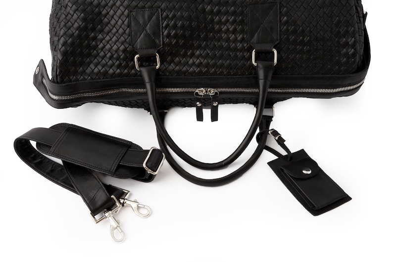 May include: Black leather woven duffel bag with a detachable shoulder strap and a small black leather tag.
