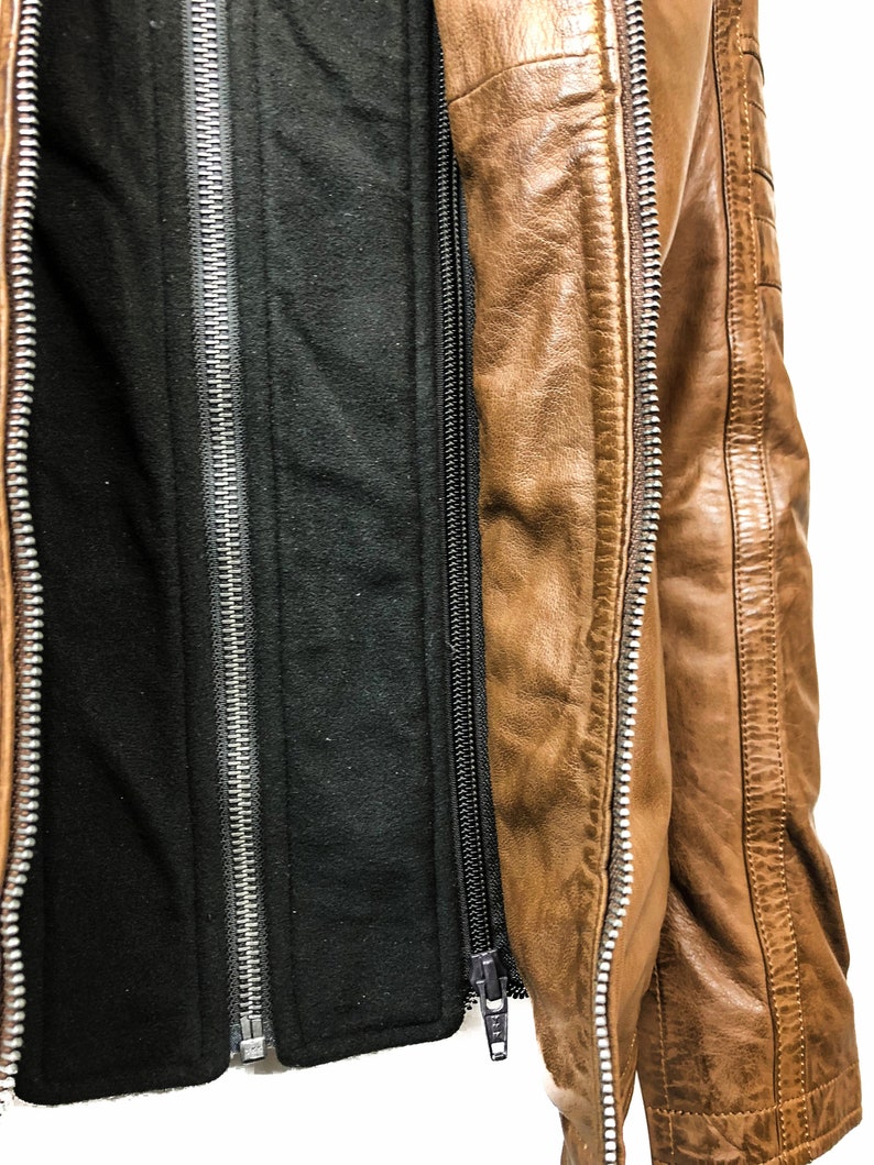 May include: A brown leather jacket with a black fleece lining. The jacket has a zipper closure and two zippered pockets.