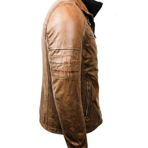 May include: A brown leather jacket with a zipper closure and a stand-up collar. The jacket has a zippered pocket on the left side and a decorative zipper on the right side.