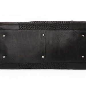 May include: Black leather travel bag with a woven design. The bag has a rectangular shape and a zipper closure.