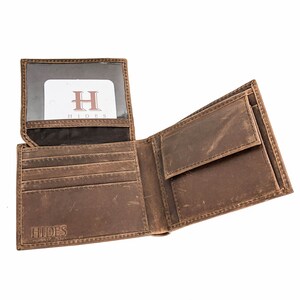 Pu&ograve; includere: Un portafoglio in pelle marrone con un design a soffietto. Il portafoglio ha pi&ugrave; slot per carte e un porta banconote. Il portafoglio ha la parola "HIDES" impressa sul davanti.