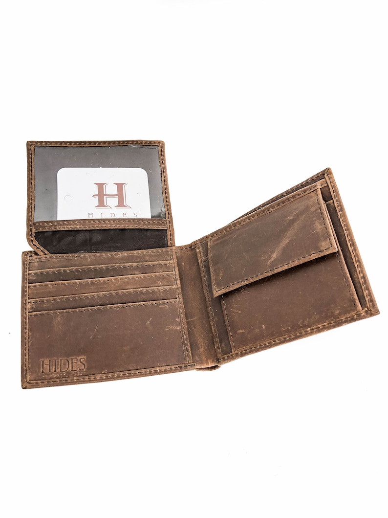 Pu&ograve; includere: Un portafoglio in pelle marrone con un design a soffietto. Il portafoglio ha pi&ugrave; slot per carte e un porta banconote. Il portafoglio ha la parola "HIDES" impressa sul davanti.