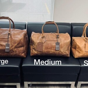 K&ouml;nnte beinhalten: Drei braune Leder-Reisetaschen in verschiedenen Gr&ouml;&szlig;en. Die Taschen sind mit "Gro&szlig;", "Mittel" und "Klein" beschriftet.