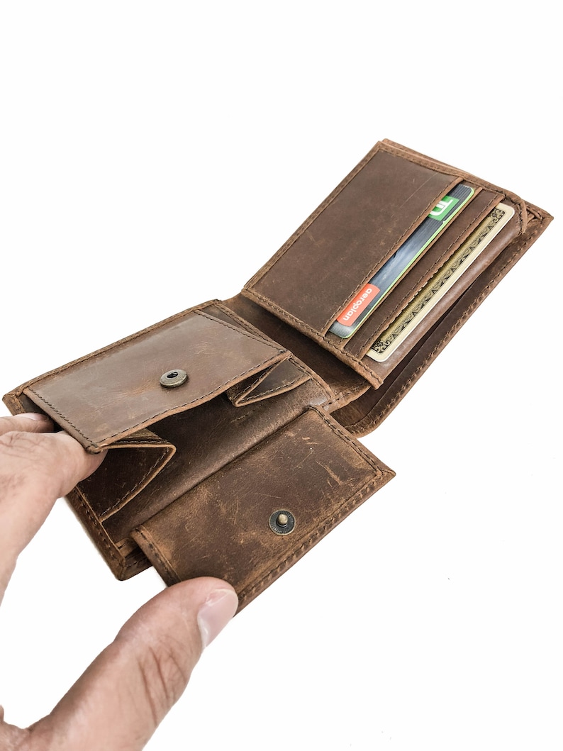Pu&ograve; includere: Un portafoglio in pelle marrone con pi&ugrave; slot per carte e un portafoglio per banconote. Il portafoglio &egrave; aperto e contiene diverse carte.