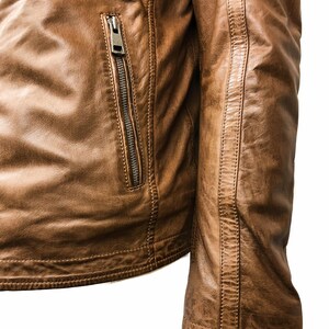 May include: A brown leather jacket with a zippered pocket on the left side and a seam detail on the right sleeve.