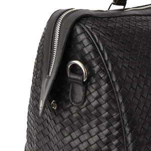 May include: Black leather woven duffel bag with a silver zipper and a silver ring handle.