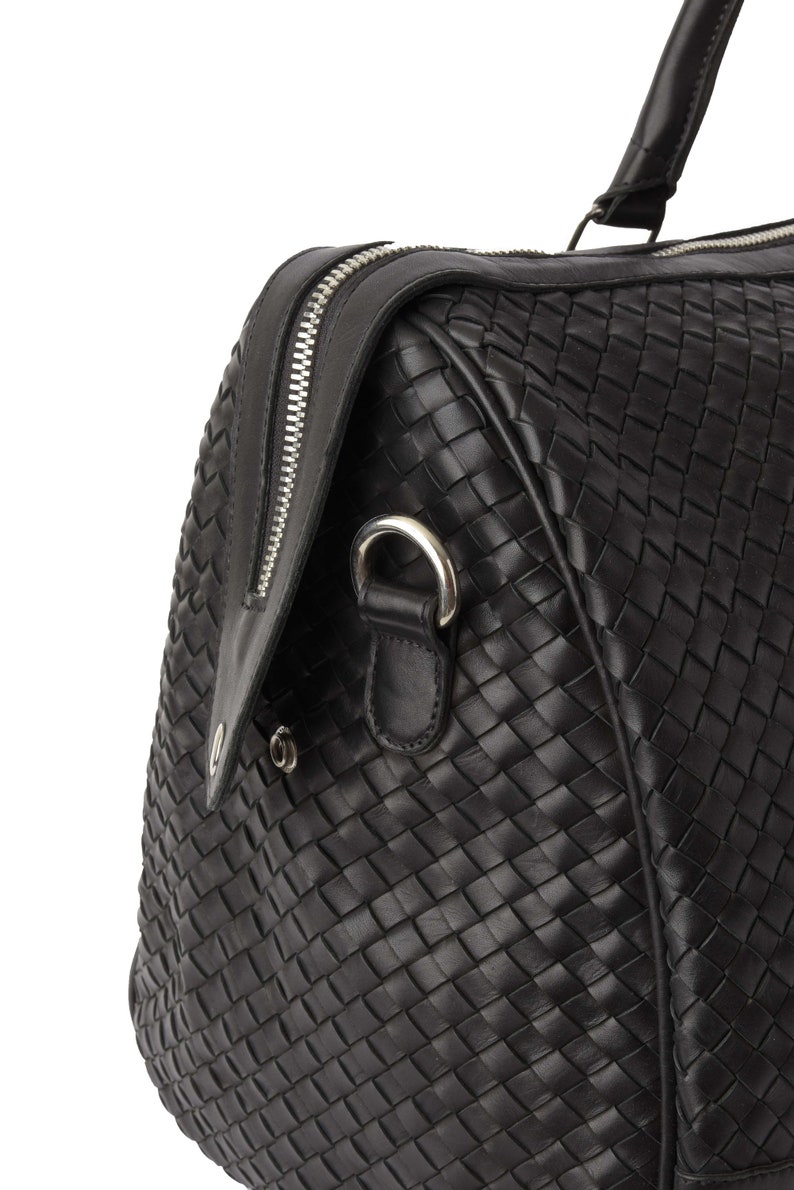 May include: Black leather woven duffel bag with a silver zipper and a silver ring handle.