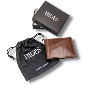 May include: A brown leather wallet with the word "HIDES" embossed on it. The wallet is in a black drawstring bag with the same logo. The wallet is also in a black box with the word "HIDES" on it.